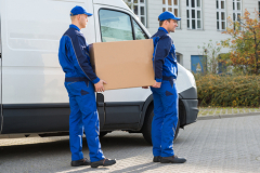 Delivery Men Carrying Cardboard Box By Truck
